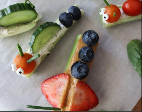Colorful snacks shaped like caterpillars and airplanes, featuring fruits and vegetables.