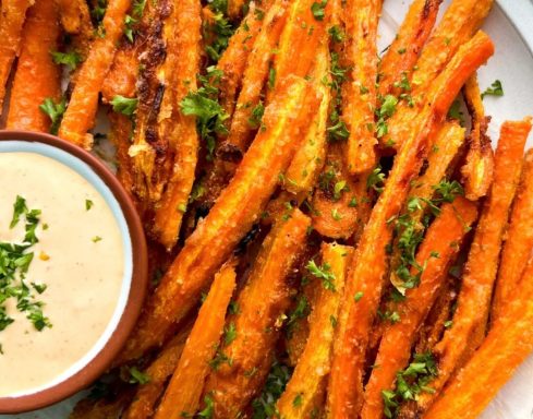 Crispy sweet potato fries served with a creamy dipping sauce and sprinkled with herbs.
