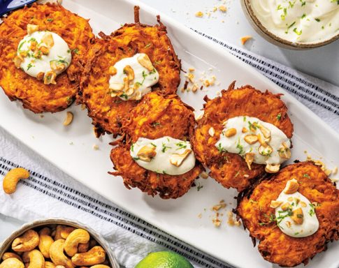 Golden-brown fritters topped with cream and cashews on a serving platter.