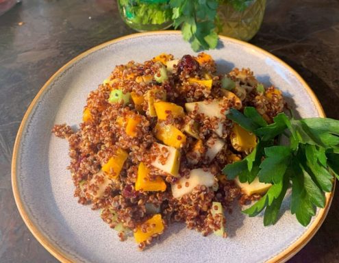 A plate of quinoa salad with roasted butternut squash, apples, and fresh herbs.